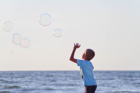 Boy on the beach chasing bubbles