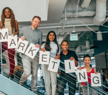 Marketing team holding signage while standing on staircase